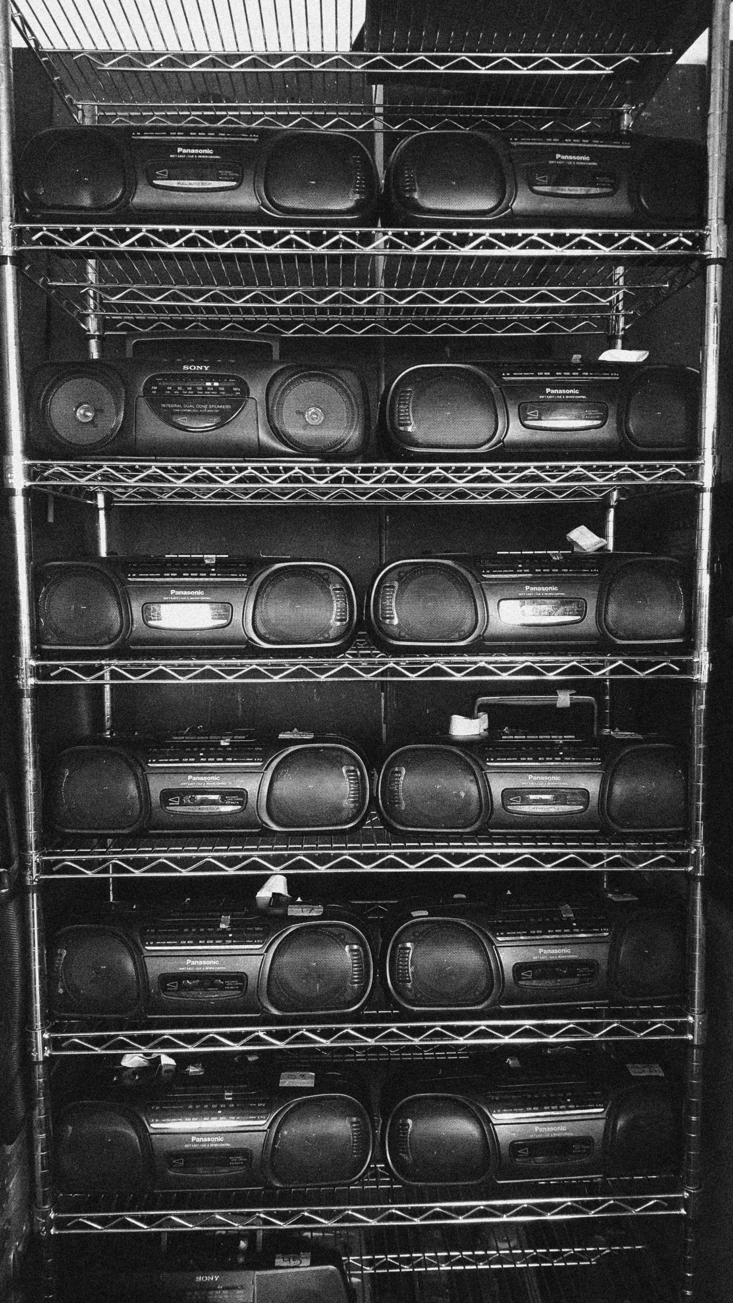 Phil Kline’s collection of vintage Panasonic RFS430 boomboxes stacked on wire shelving, black and white
