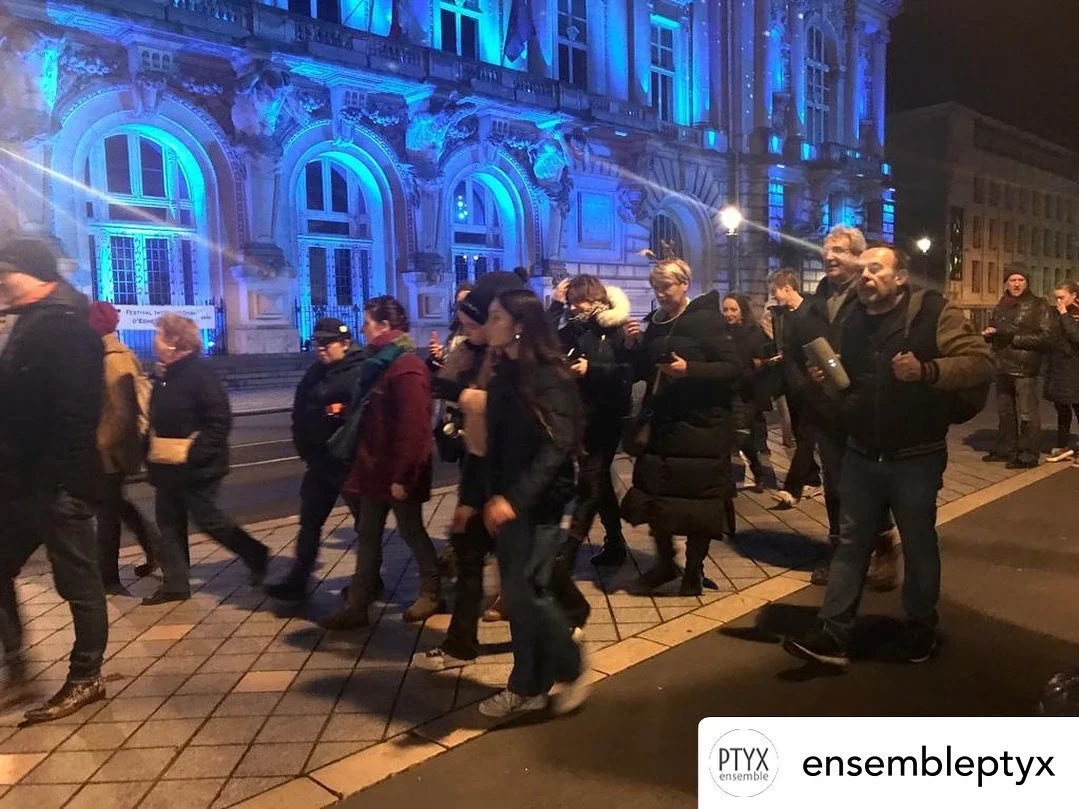 Unsilent Night participants walking past an illuminated blue-lit building at night in France