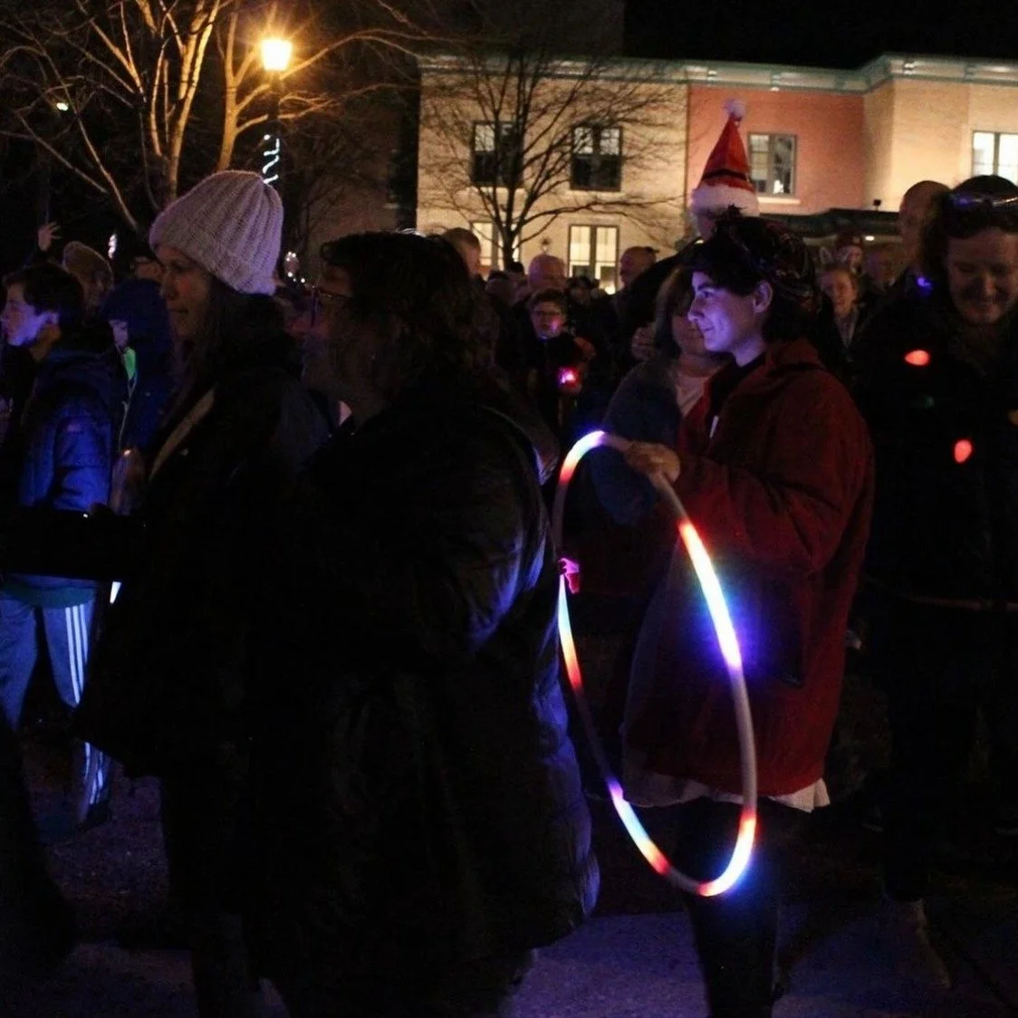 Unsilent Night participants in a nighttime crowd, one holding a glowing LED hoop