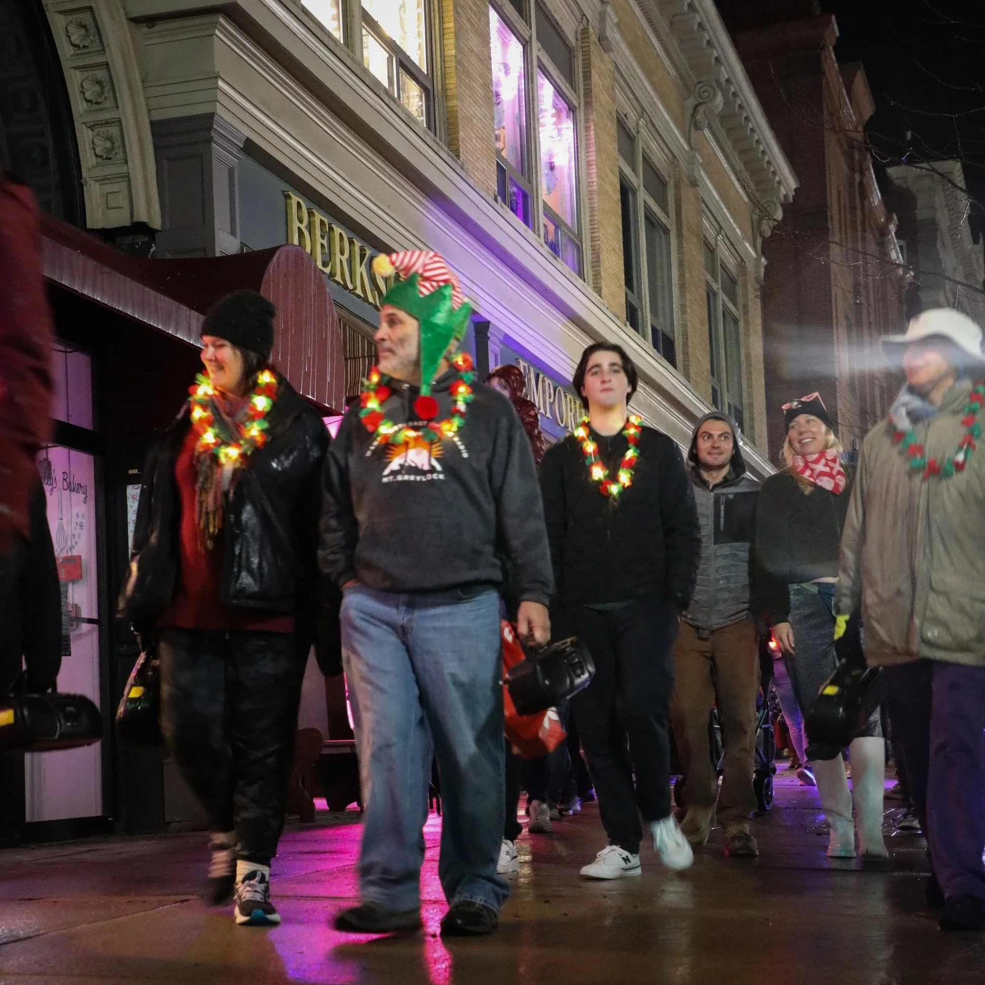 Unsilent Night participants walking down a lit city street at night wearing glowing light-up leis