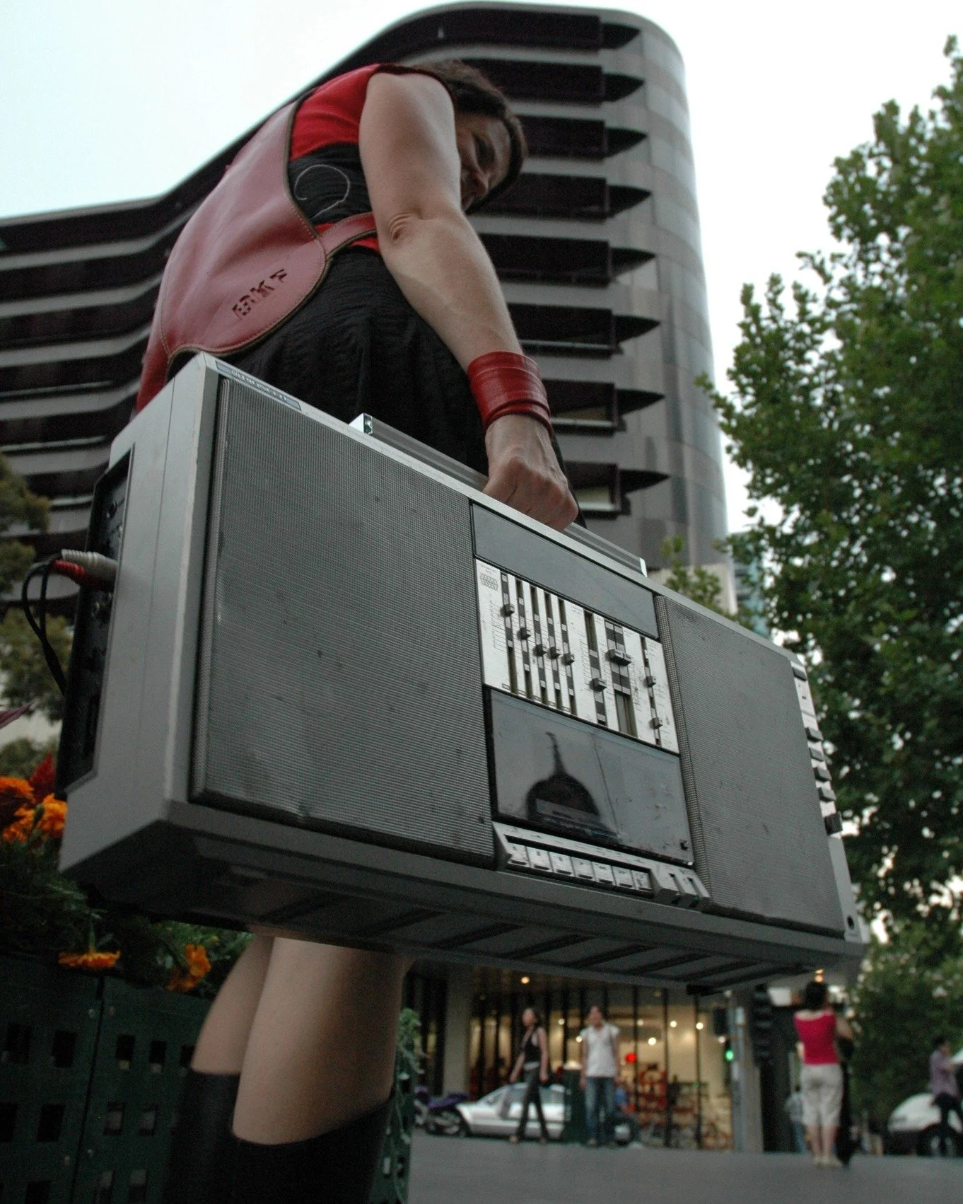Person holding a large vintage boombox overhead on a city street